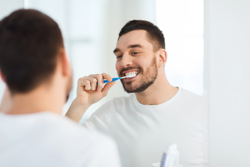 man brushing his teeth in the mirror