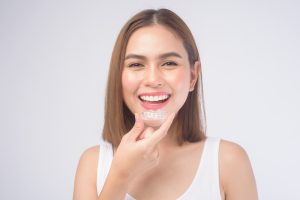 A,Young,Smiling,Woman,Holding,Invisalign,Braces
